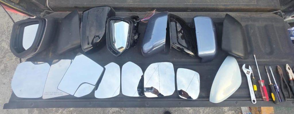 robo de autopartes - Punto Critico Assortment of car side mirror housings, mirror glass panels, and repair tools laid out on a tailgate.
